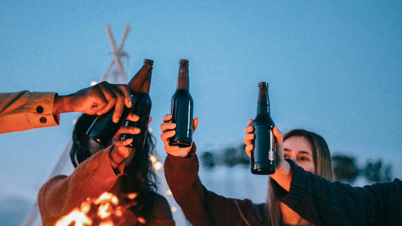 Backpackers drinking beers around a campfire